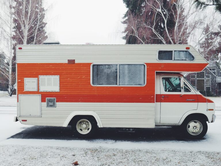 orange and white class-a RV surrounded by snow